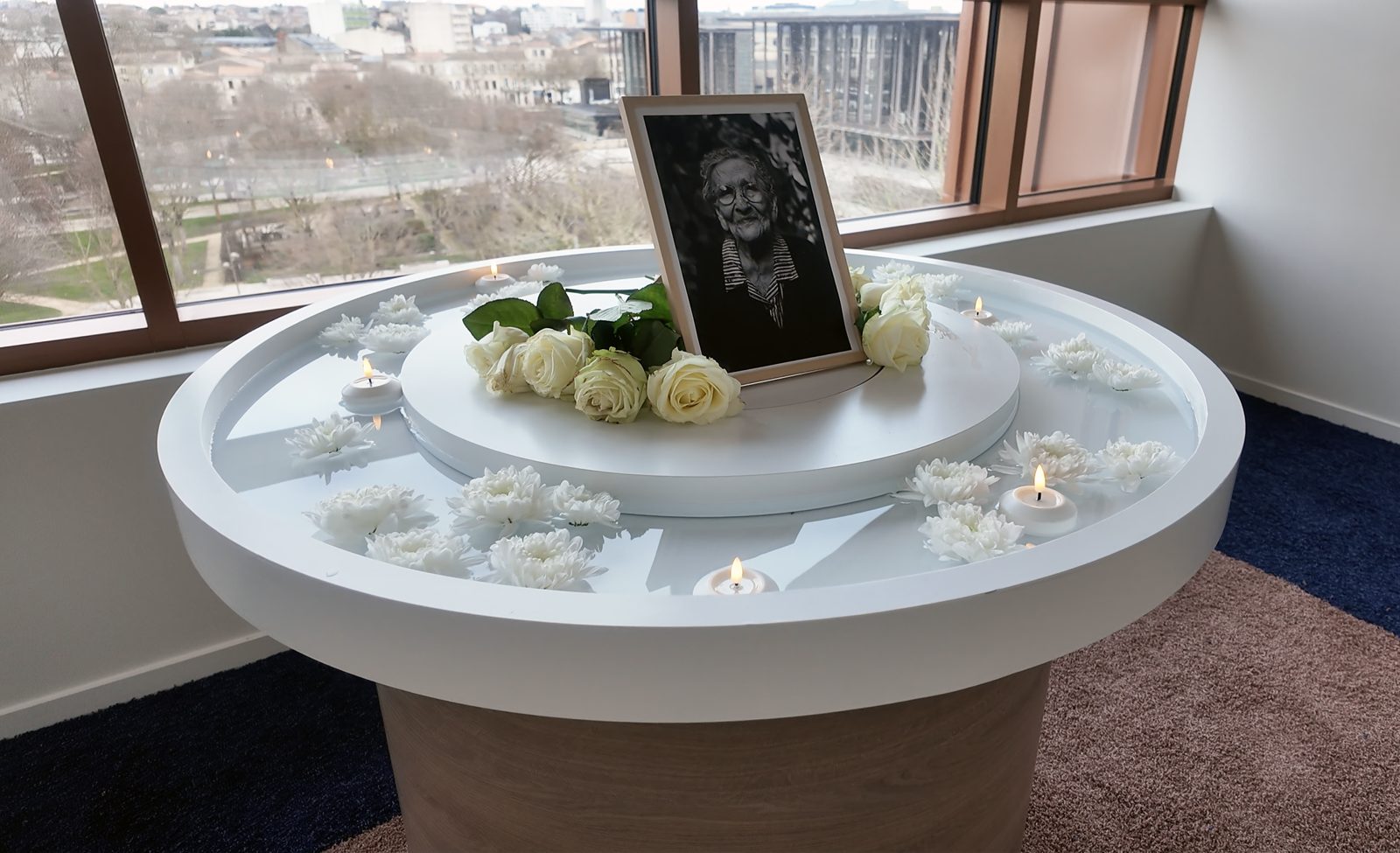 L'autel La Source aménagé en espace commémoratif avec portrait, fleurs blanches et bougies