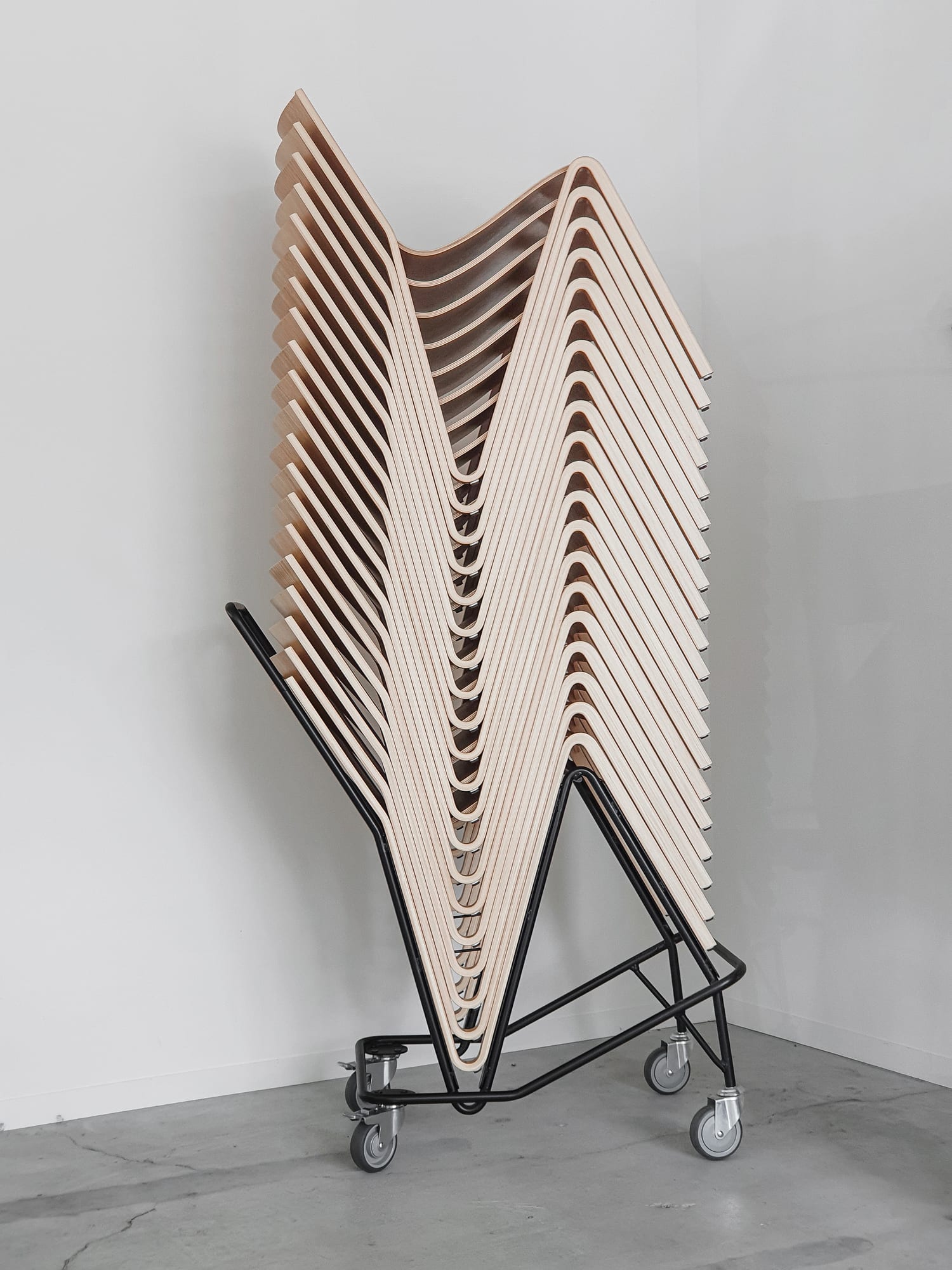Une pile de chaises Zesty sur son chariot de transport dédié, illustrant leur faible encombrement