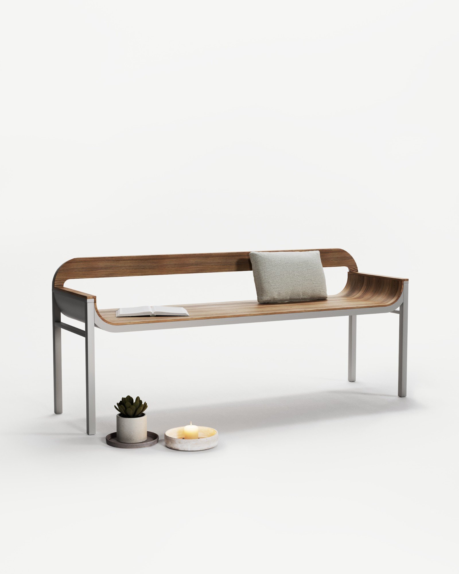 Le banc Versõ, assise et dossier en bois cintré sur piètement métal, mis en scène avec un coussin, un livre et une bougie